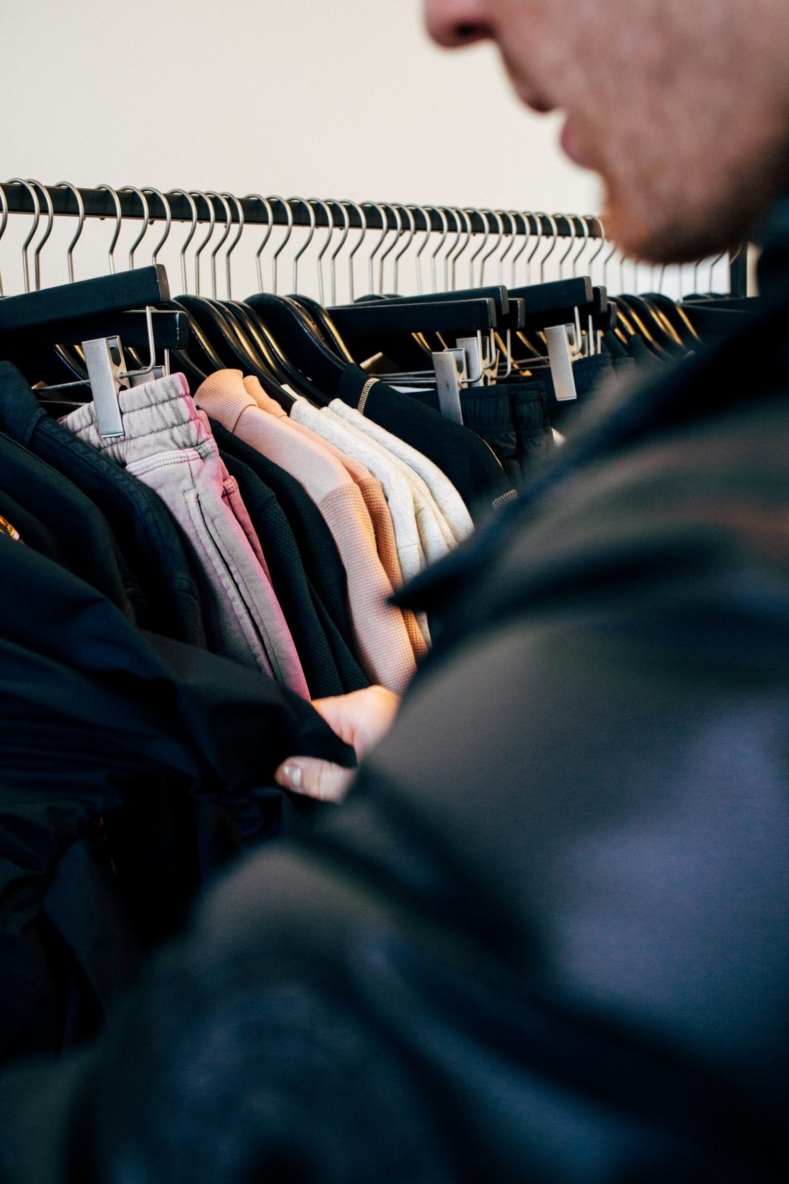man in black jacket standing near clothes rack